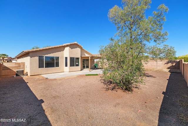 rear view of house with a tile roof, stucco siding, a fenced backyard, cooling unit, and a patio