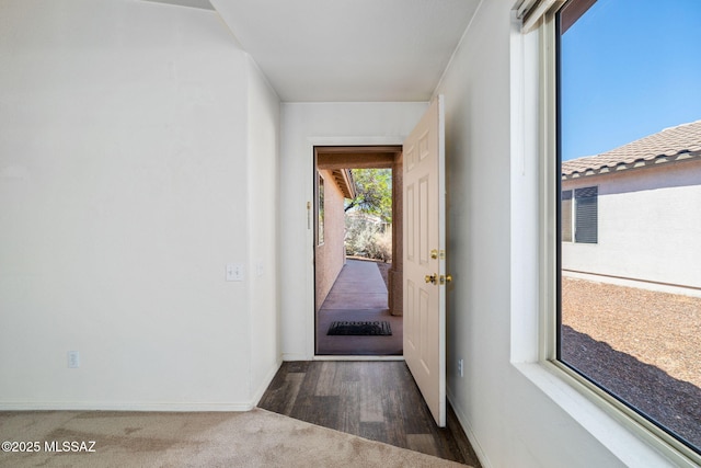 doorway to outside featuring carpet floors and baseboards