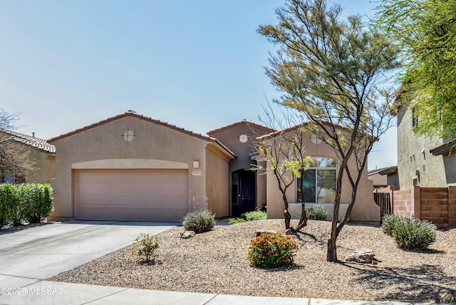 view of front of house featuring a tiled roof, stucco siding, fence, a garage, and concrete driveway