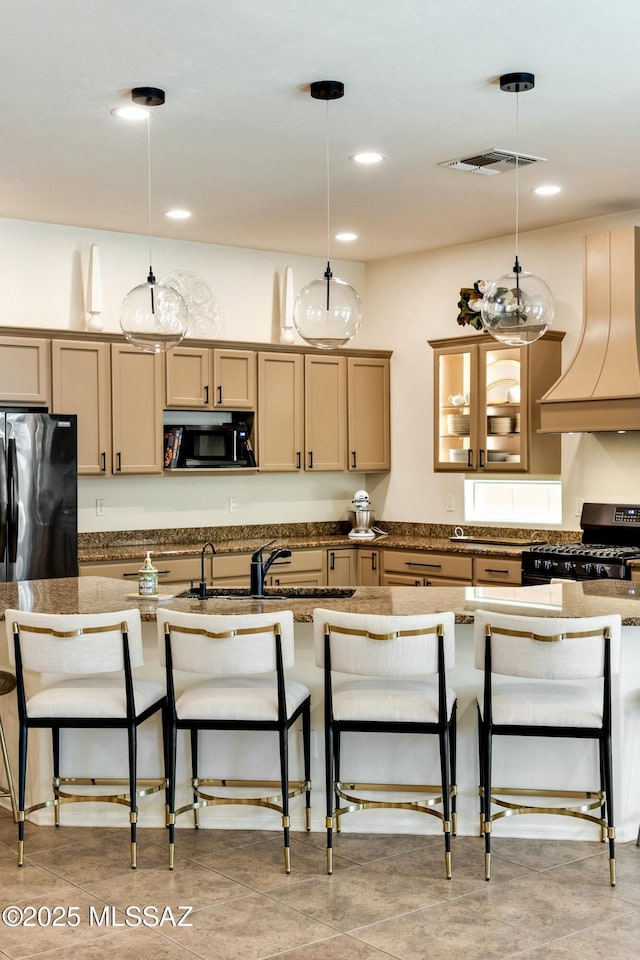 kitchen with hanging light fixtures, custom range hood, a kitchen bar, appliances with stainless steel finishes, and visible vents