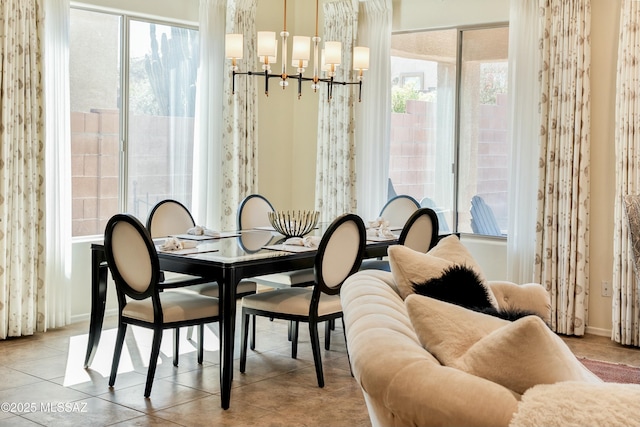 tiled dining space featuring baseboards and a chandelier