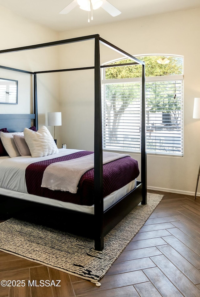 bedroom featuring a ceiling fan, baseboards, and multiple windows