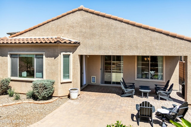 back of property featuring a patio area, a tile roof, and stucco siding