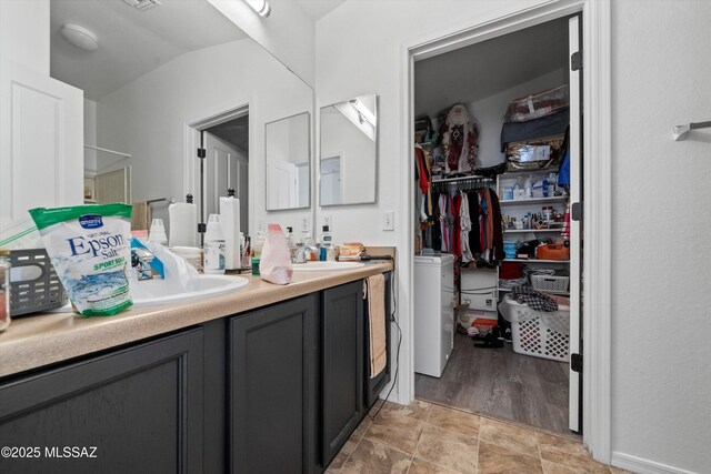 bathroom with double vanity, a sink, and washer / dryer