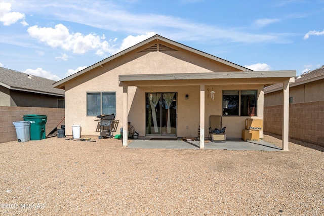 rear view of house featuring a patio area, stucco siding, and fence