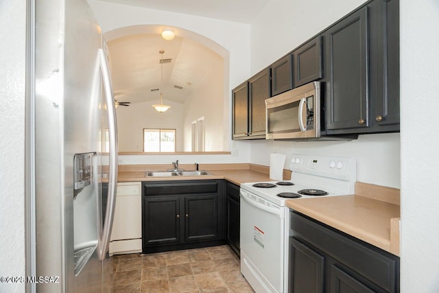 kitchen with arched walkways, a sink, lofted ceiling, light countertops, and appliances with stainless steel finishes