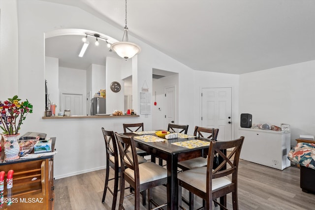 dining space with vaulted ceiling and wood finished floors
