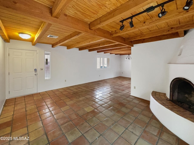 unfurnished living room featuring beamed ceiling, tile patterned flooring, a fireplace with raised hearth, visible vents, and wooden ceiling