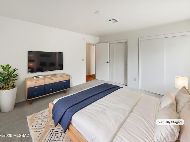 carpeted bedroom featuring visible vents and multiple closets
