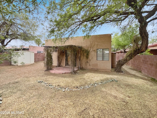rear view of property with a fenced backyard, stucco siding, and a patio area