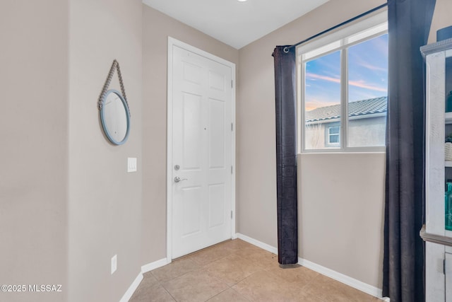 entryway with baseboards and light tile patterned flooring
