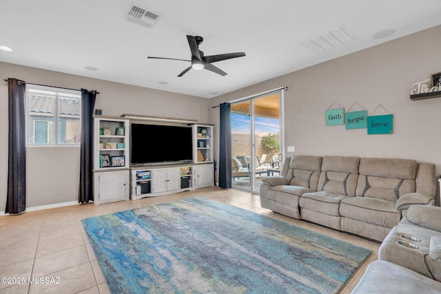 tiled living room with a ceiling fan, visible vents, and a wealth of natural light