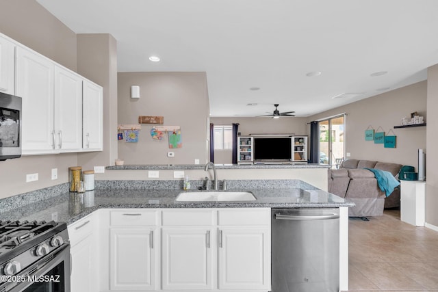 kitchen with a sink, open floor plan, ceiling fan, appliances with stainless steel finishes, and a peninsula