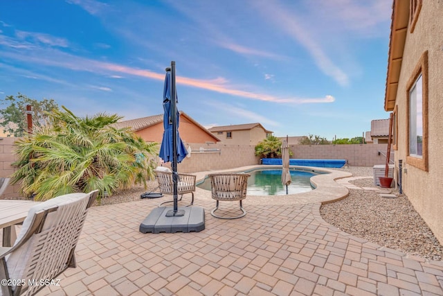 pool at dusk featuring a fenced in pool, a patio area, and a fenced backyard