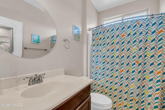 bathroom featuring toilet, vanity, and a shower with curtain