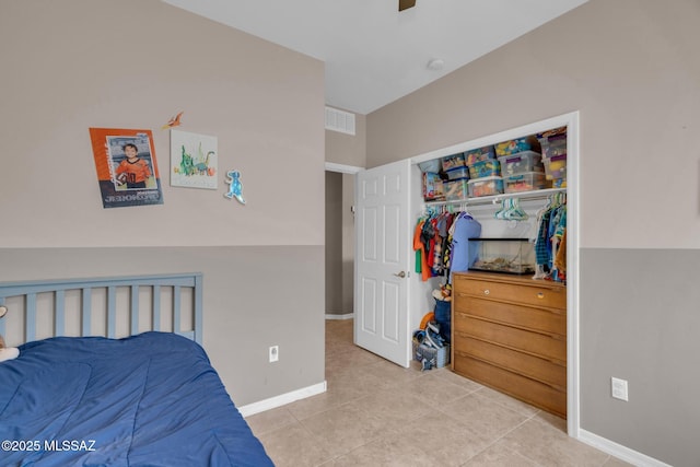 tiled bedroom with a closet, visible vents, baseboards, and a ceiling fan
