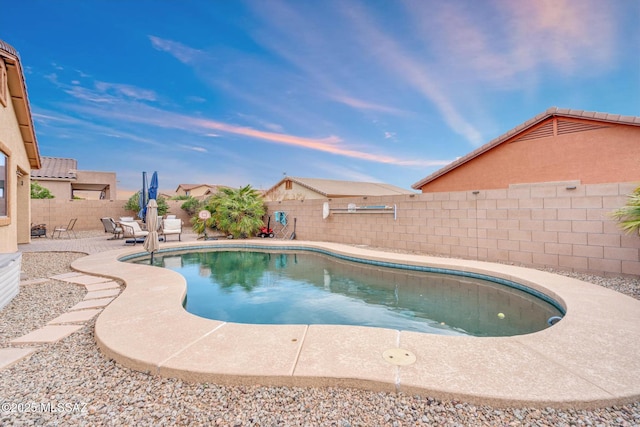 pool at dusk with a fenced backyard, a fenced in pool, and a patio
