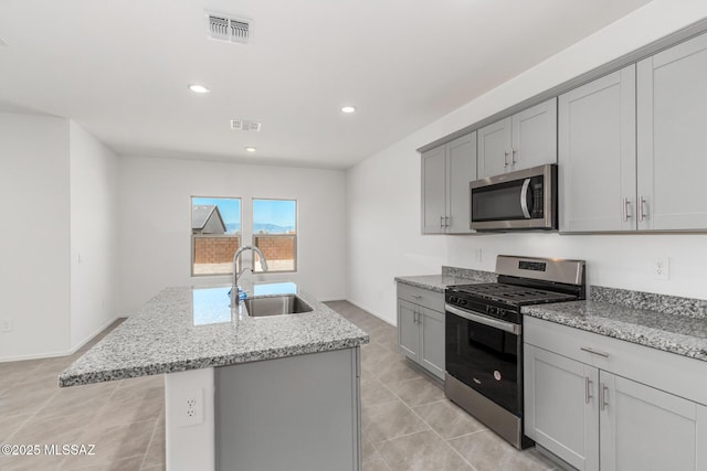 kitchen with gray cabinets, an island with sink, visible vents, appliances with stainless steel finishes, and a sink