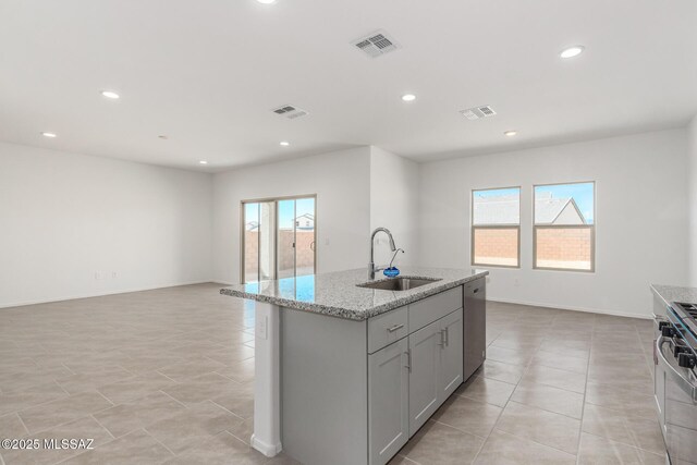 kitchen with range, stainless steel dishwasher, an island with sink, visible vents, and a sink