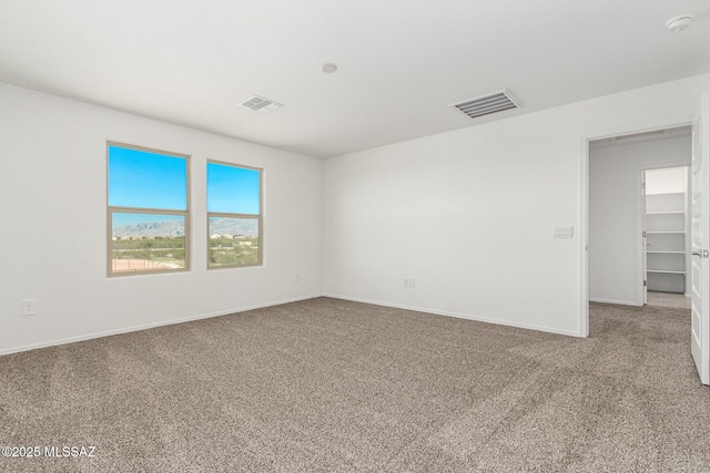 spare room with carpet flooring, visible vents, and baseboards