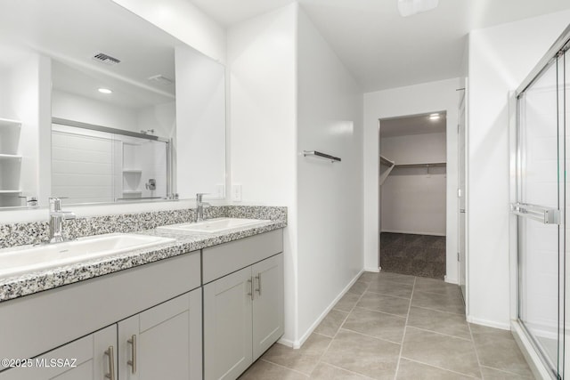 full bathroom with a sink, a spacious closet, a shower stall, and double vanity