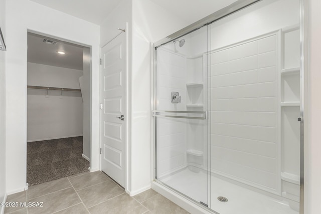 bathroom with visible vents, a walk in closet, a stall shower, baseboards, and tile patterned floors