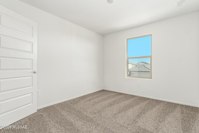 unfurnished room featuring carpet and baseboards