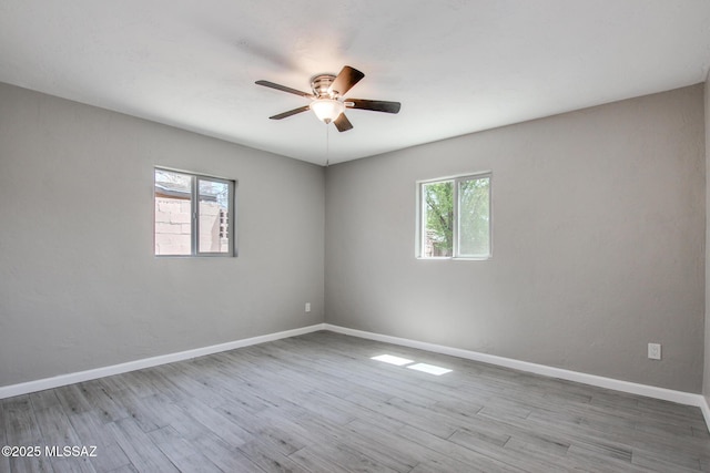 empty room with wood finished floors, baseboards, and a ceiling fan
