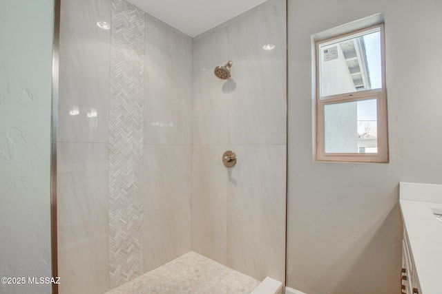 bathroom featuring a tile shower and vanity