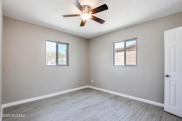 spare room with wood finished floors, a ceiling fan, and plenty of natural light