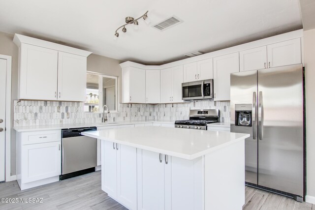 kitchen with a center island, white cabinetry, visible vents, and stainless steel appliances
