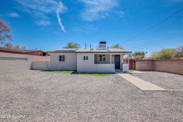 view of front of property with a fenced backyard, stucco siding, and solar panels