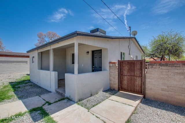 bungalow with fence, cooling unit, a gate, and stucco siding