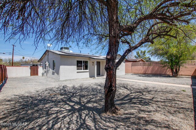 single story home featuring roof mounted solar panels, stucco siding, fence private yard, and a chimney