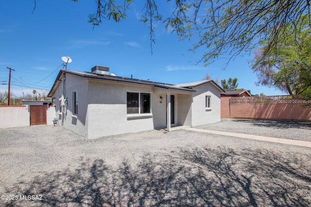 back of property featuring fence, cooling unit, and stucco siding