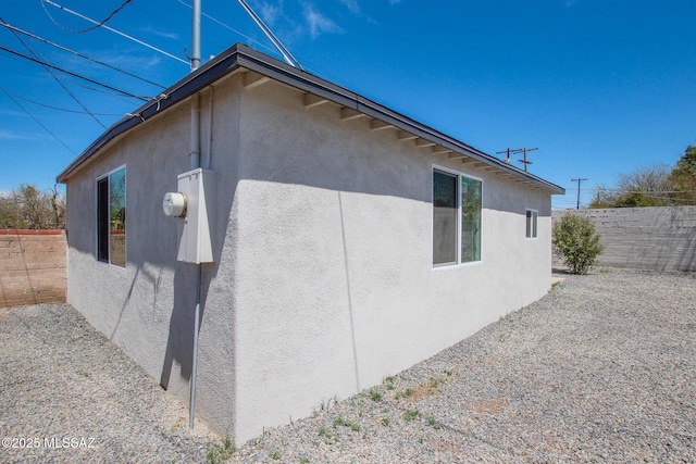 view of property exterior with stucco siding and fence