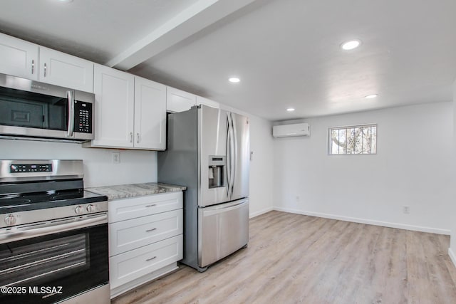 kitchen with baseboards, white cabinetry, stainless steel appliances, light wood-style flooring, and a wall unit AC