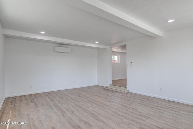 empty room featuring a wall mounted AC, wood finished floors, and baseboards