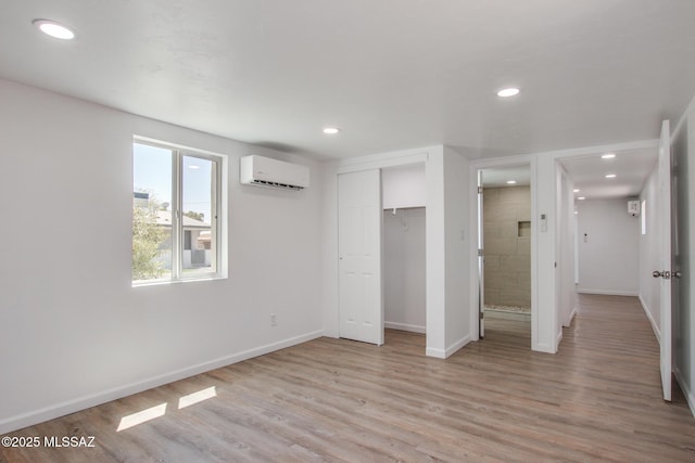 unfurnished bedroom with recessed lighting, light wood-style flooring, baseboards, and a wall unit AC