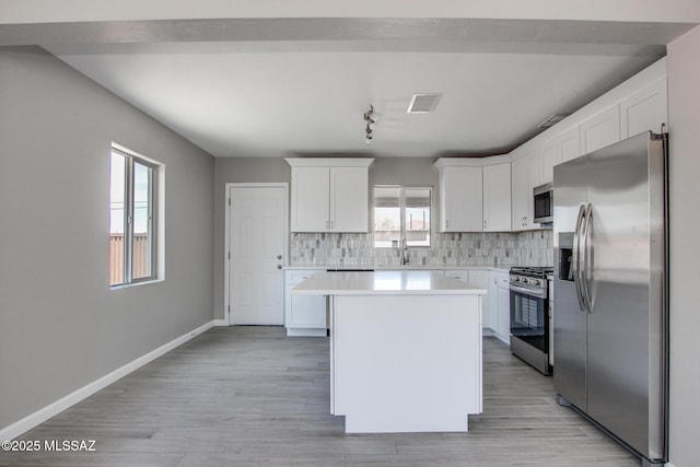 kitchen with light countertops, white cabinetry, a kitchen island, visible vents, and appliances with stainless steel finishes