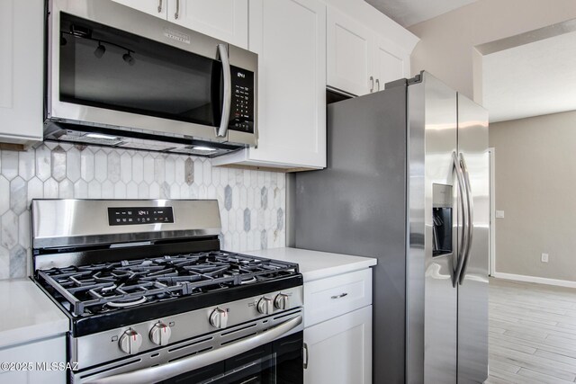 kitchen with light wood-style flooring, tasteful backsplash, white cabinetry, appliances with stainless steel finishes, and light countertops