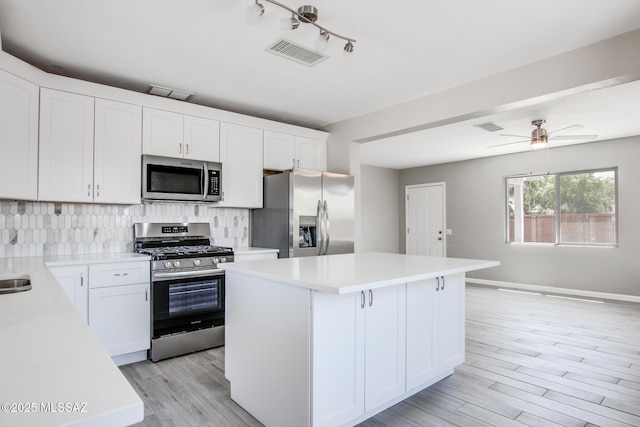 kitchen featuring tasteful backsplash, a center island, light countertops, visible vents, and appliances with stainless steel finishes