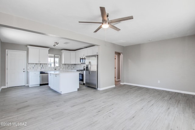 kitchen with a ceiling fan, a kitchen island, appliances with stainless steel finishes, light countertops, and open floor plan