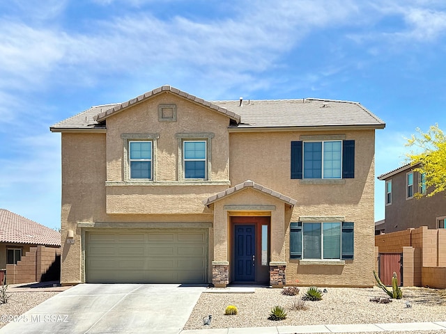 traditional-style house featuring fence, stucco siding, driveway, and a garage