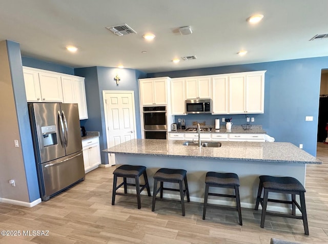 kitchen featuring stainless steel appliances, visible vents, a sink, and light wood-style flooring