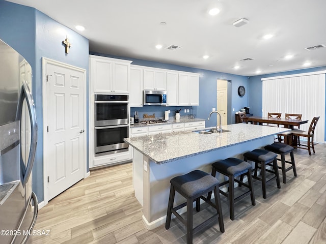 kitchen featuring visible vents, a sink, light wood finished floors, and stainless steel appliances