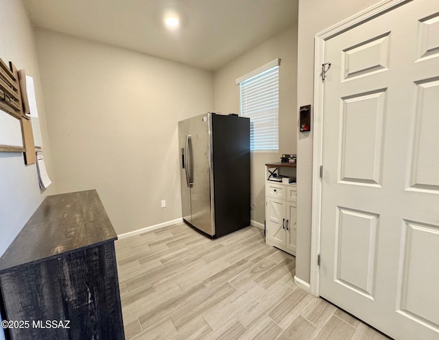 kitchen with dark countertops, baseboards, stainless steel fridge, and light wood finished floors