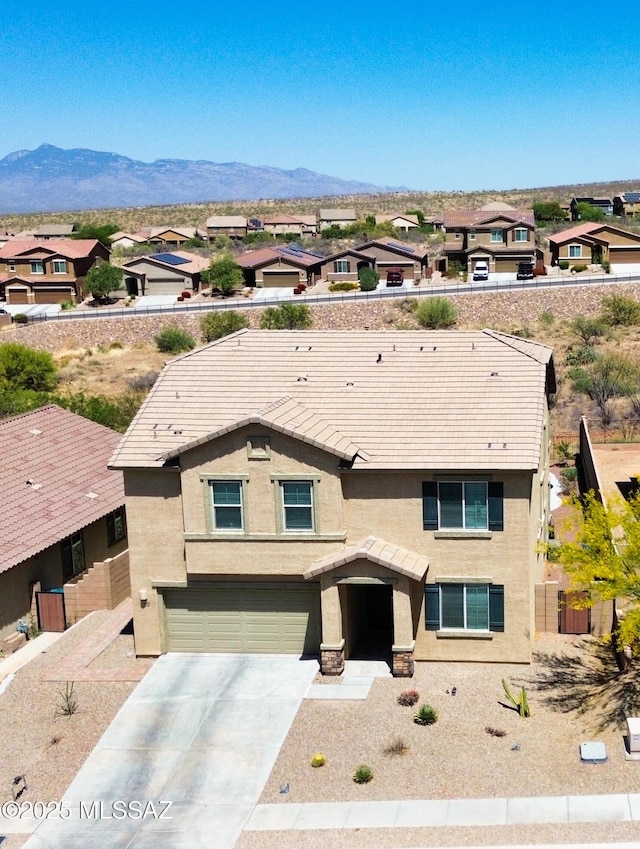 view of front of house featuring concrete driveway, stucco siding, a mountain view, and a garage