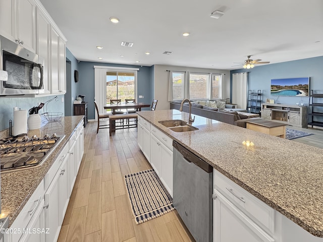 kitchen featuring white cabinets, stainless steel appliances, stone countertops, and a sink