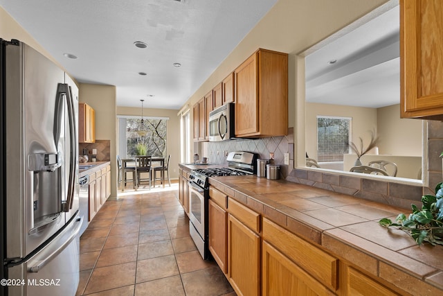 13792 E Langtry Ln, Tucson, AZ 85747 - kitchen with tile countertops, stainless steel appliances, decorative light fixtures, tile patterned floors, and backsplash